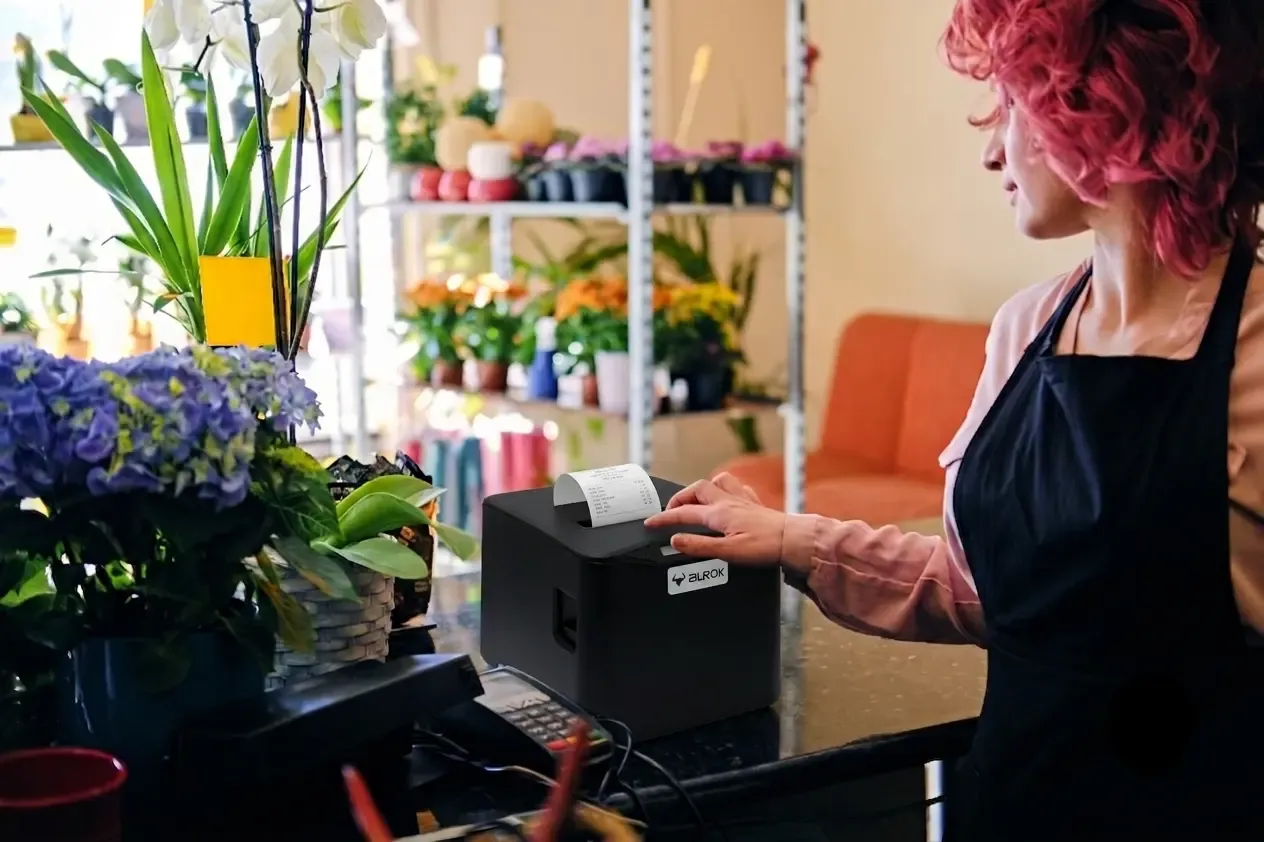 AUROK thermal receipt printer printing a slip at a flower shop checkout counter